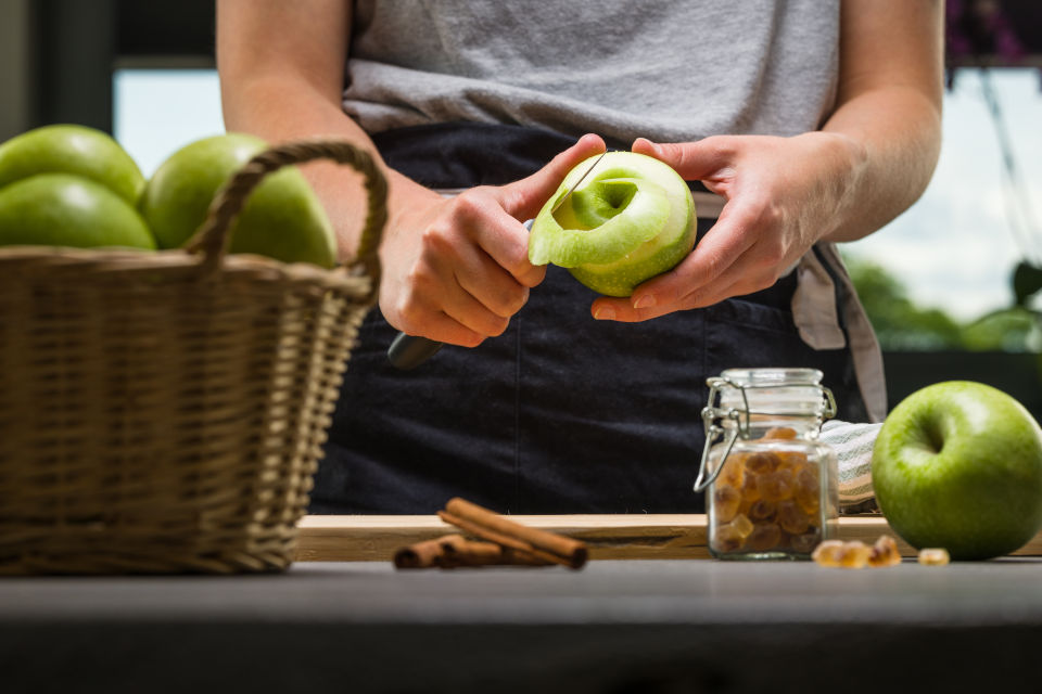 Frau schält einen Apfel mit einem scharfen Messer